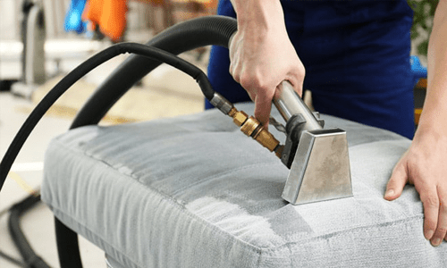 A person using a steam cleaner to clean upholstery