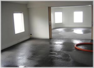 Wet floor cleaning with orange hose in room.