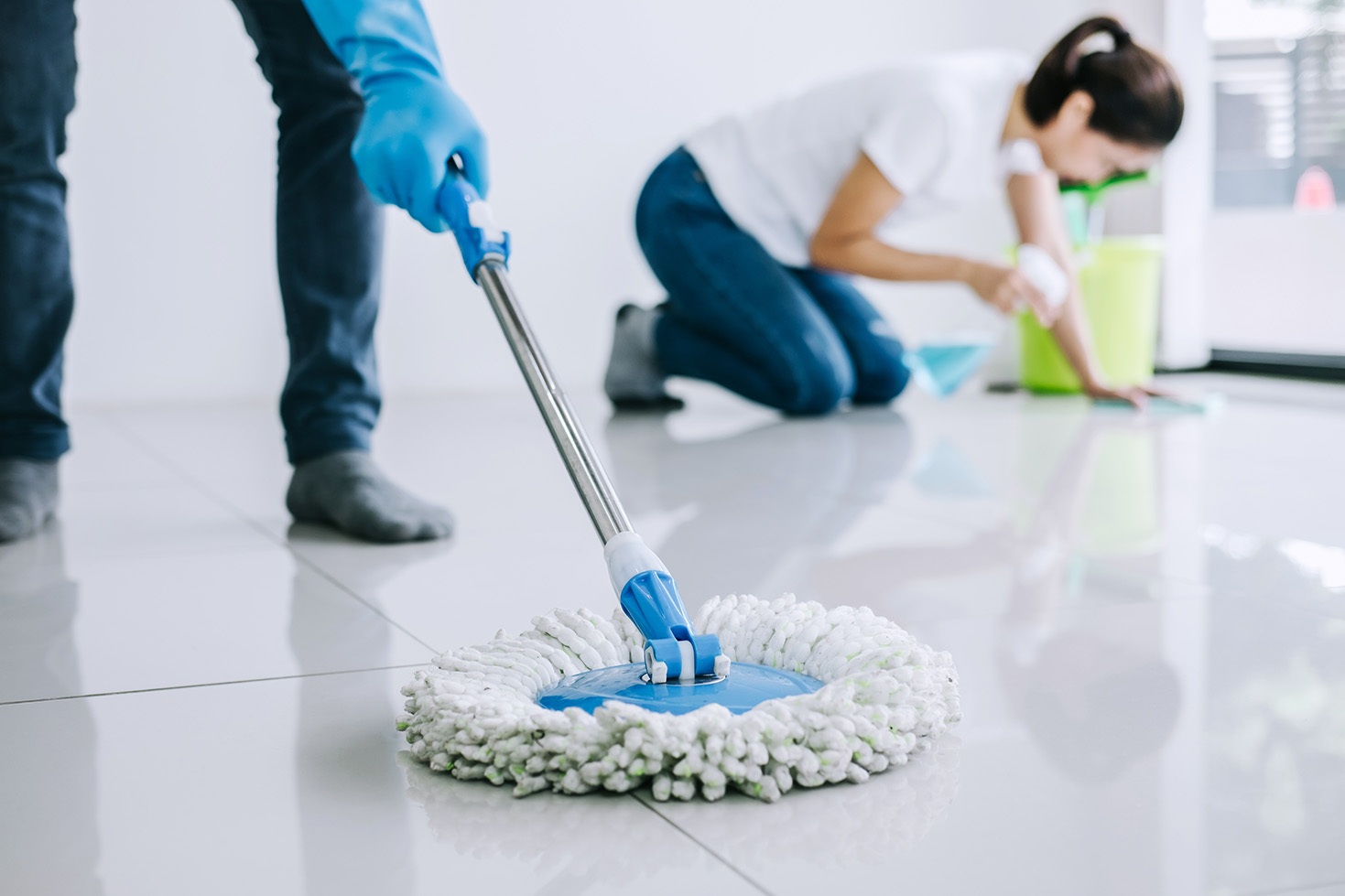 People cleaning floor with mop and bucket.